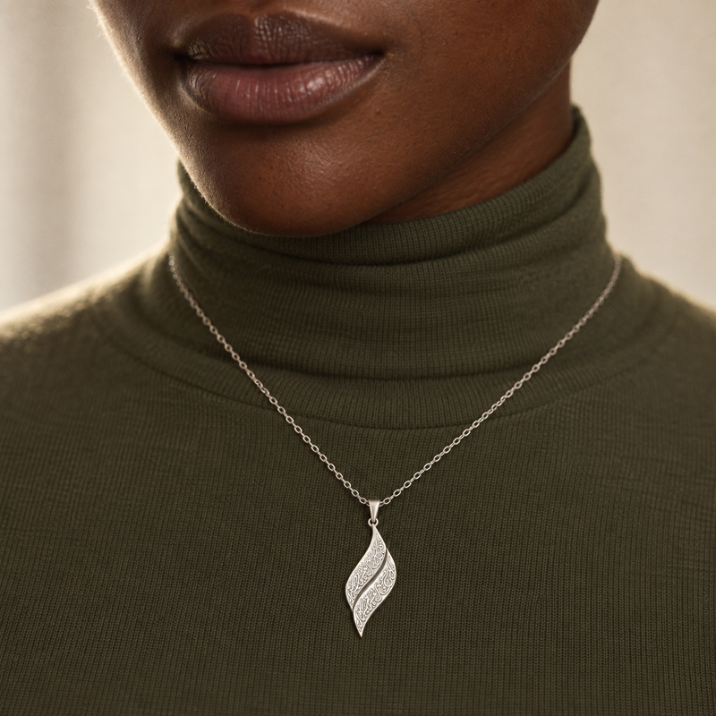 Silver engraved leaf pendant worn over an olive knit turtleneck