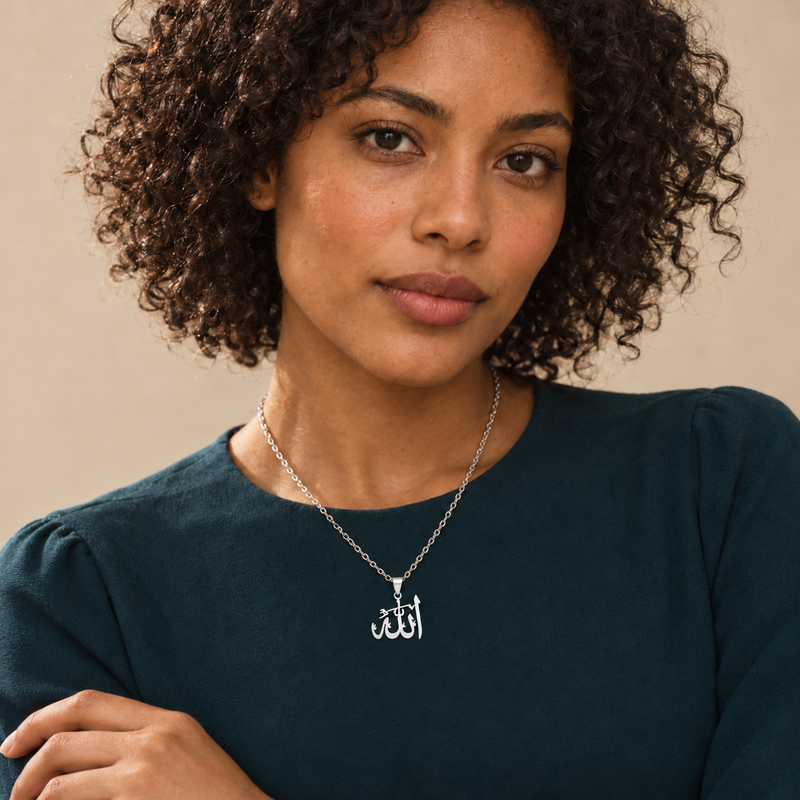 Silver Jalal calligraphy pendant worn over a deep teal top