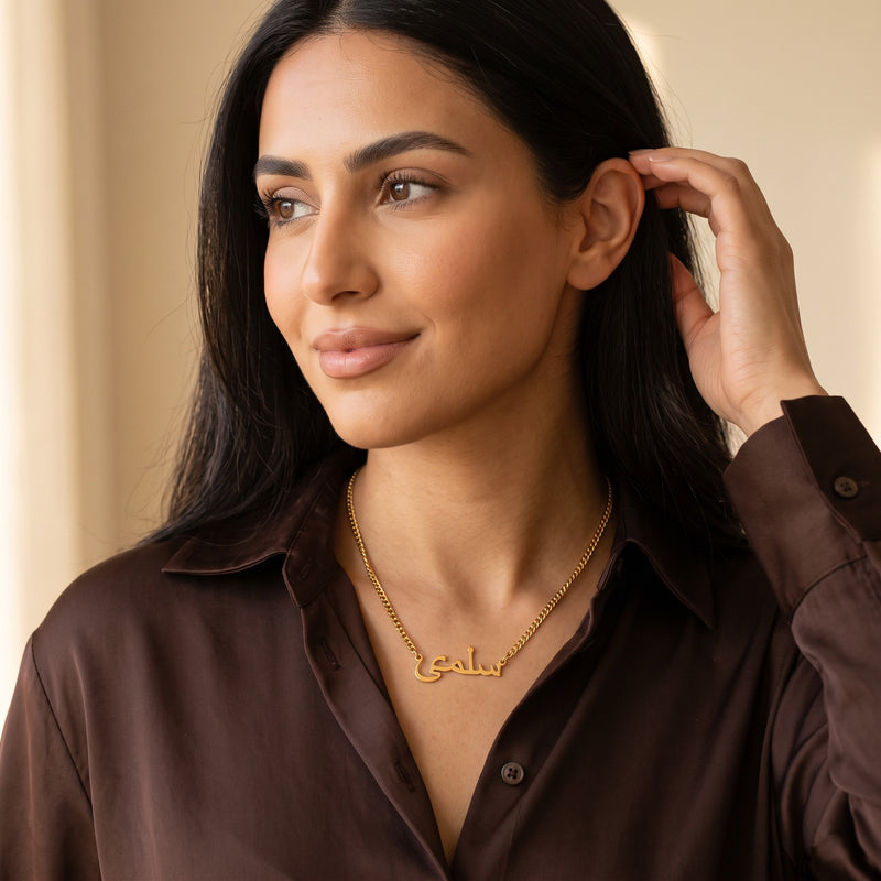 Gold Arabic name necklace on curb chain worn with a silk shirt