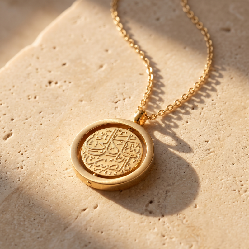 Gold Noor spinning pendant resting on travertine stone in sunlight