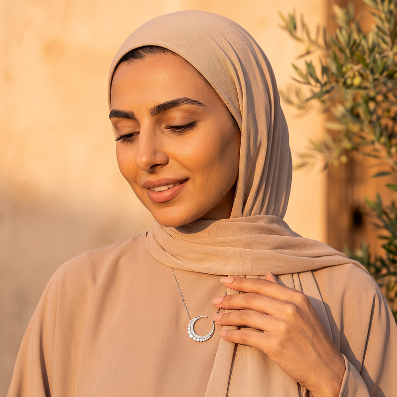 Woman in hijab touching her Hilal Al-Noor crescent necklace