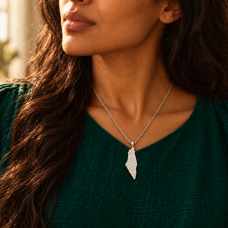 Palestine map necklace worn, silver pendant on an emerald neckline