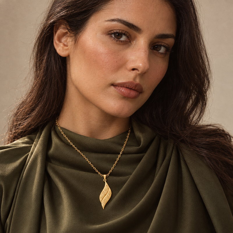Gold calligraphy leaf necklace worn over an olive silk neckline