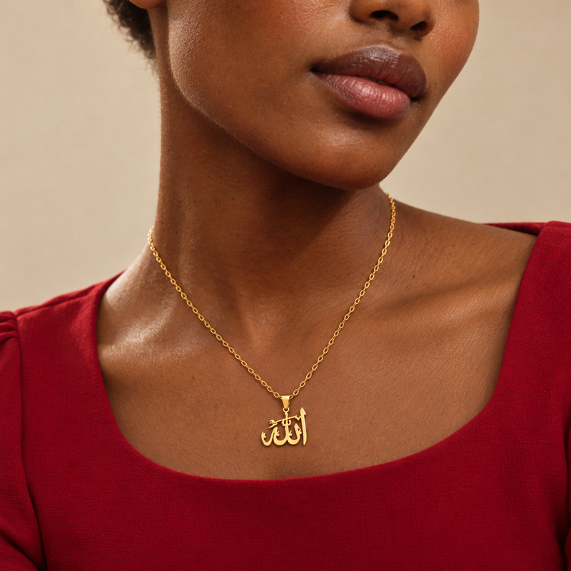 Close-up of the gold Jalal calligraphy pendant resting below the collarbone