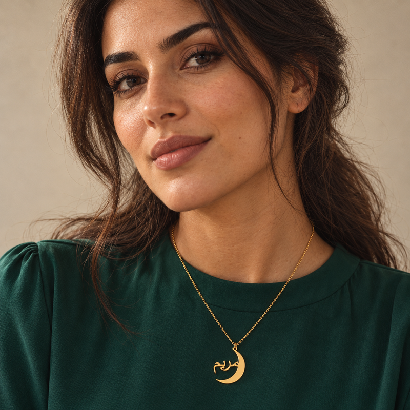 Gold crescent name necklace worn over an emerald green top