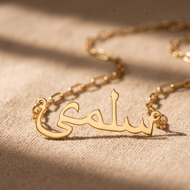 Gold paperclip chain name necklace on linen