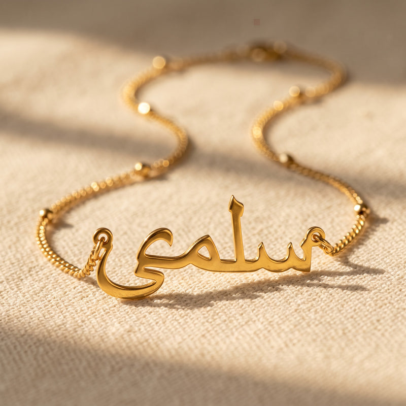Close-up of the gold Arabic name necklace on its beaded satellite chain