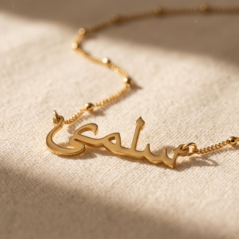 Gold satellite chain name necklace on linen