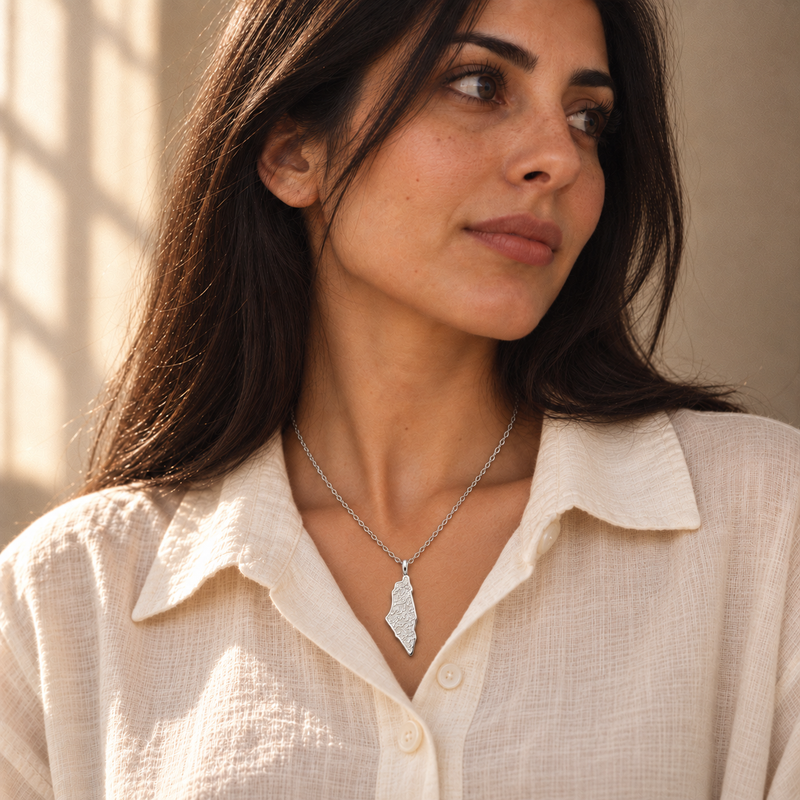 Palestine map necklace worn, silver engraved pendant on cream linen